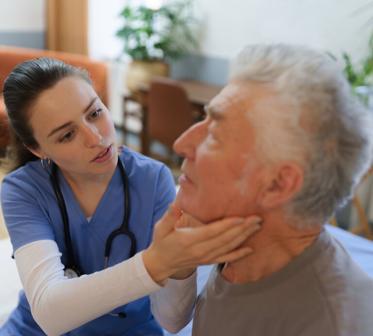 Eine Ärztin untersucht die Lymphknoten eines Patienten. | © IMAGO / HalfPoint Images
