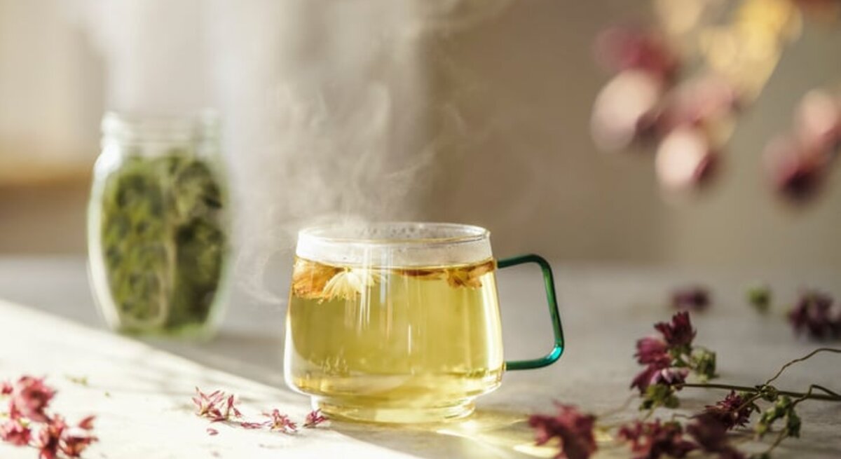 Frisch aufgebrühter Kräutertee in einer Glastasse auf dem Küchentisch.