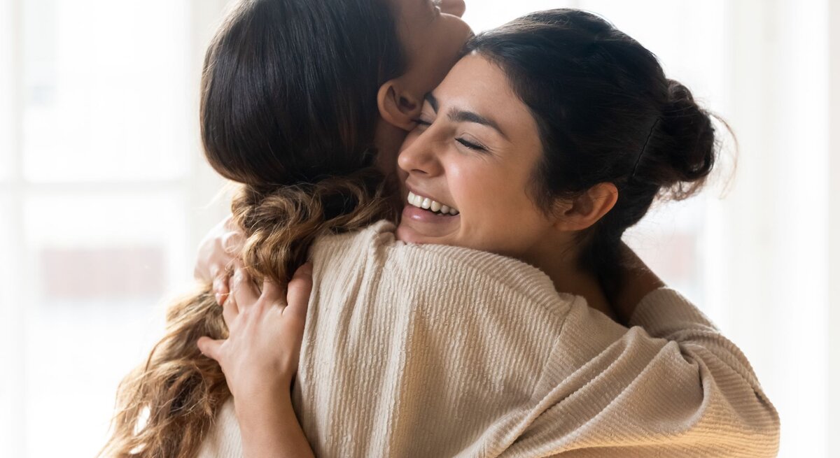 Zwei Frauen umarmen sich innig und lächeln dabei