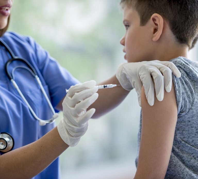 Ein Junge bekommt von einer Krankenschwester eine Impfspritze in den Oberarm. | © gettyimages/FatCamera