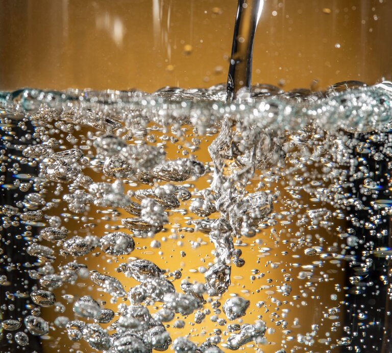 Wasser mit Kohlensäure wird in ein Glas gegossen und sprudelt. | © IMAGO / Wolfgang Maria Weber