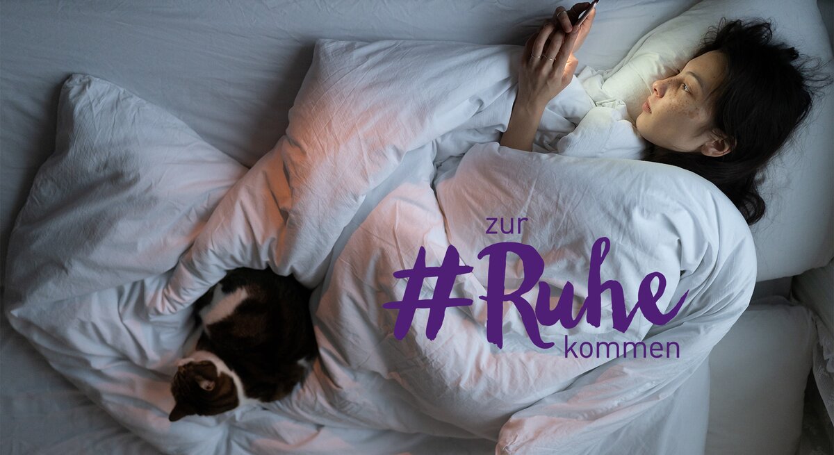 Frau liegt im Bett mit Handy in der Hand
