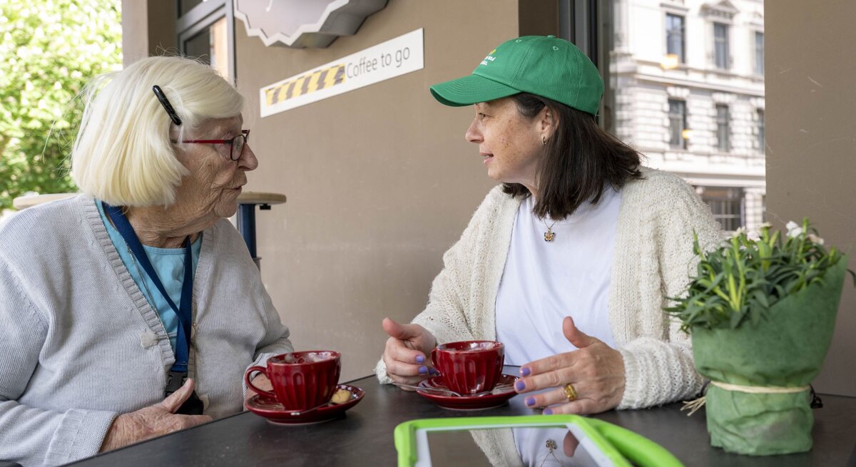 Preisträgerin Mitra Kassai mit einer Seniorin im Gespräch an einem Tisch