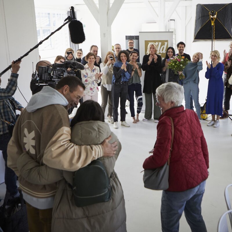 Eine Gruppe applaudierender Menschen umringt ein Paar, das sich umarmt, während ein Kamerateam die Szene filmt. | © dsphotos.de
