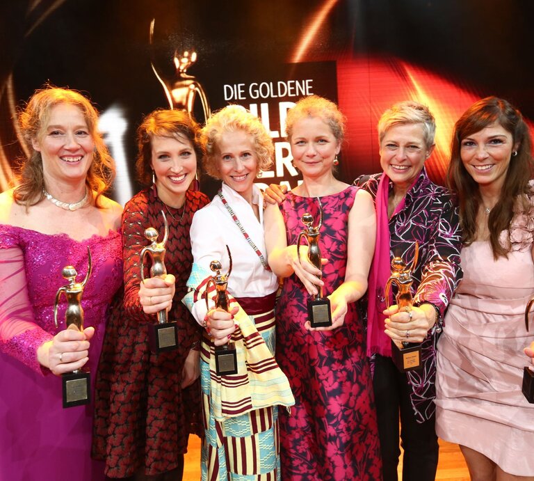 Sechs Preisträgerinnen der GOLDENEN BILD der FRAU-Gala 2017 halten in Abendgarderobe ihren goldenen Preis in die Kamera  | © Guido Ohlenbostel
