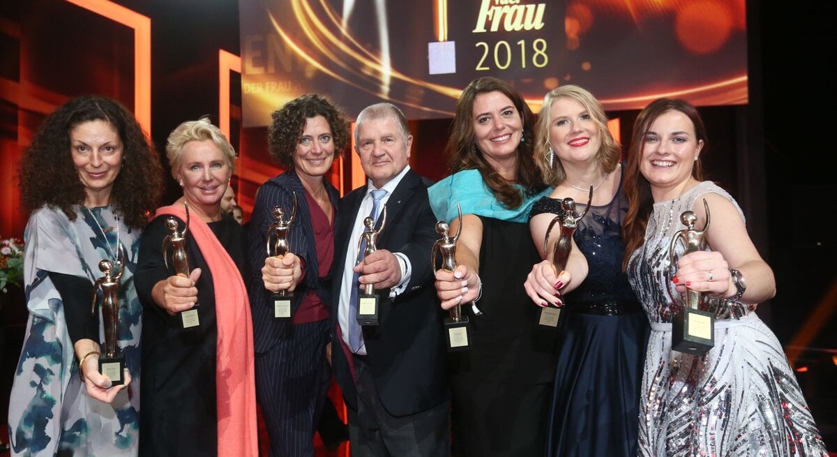 Sechs Preisträgerinnen in Abendkleidern und ein Mann der GOLDENEN BILD der FRAU-Gala 2018 halten ihre goldene Figurine in die Kamera 