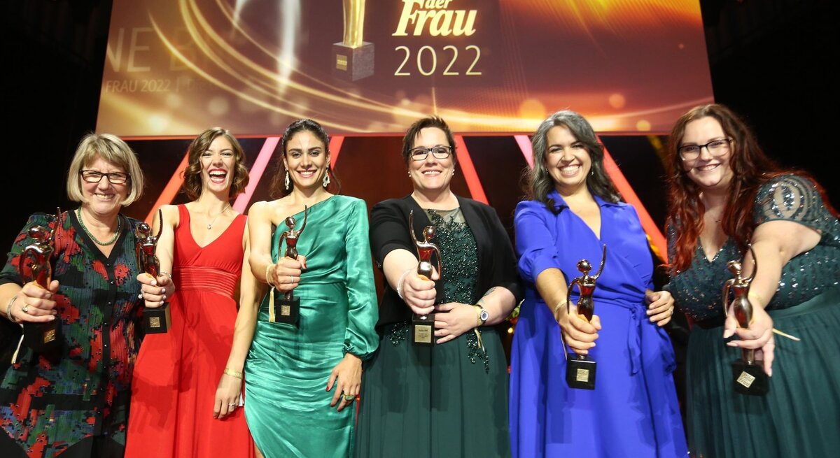 Sechs Preisträgerinnen in Abendkleidern auf der Bühne der GOLDENEN BILD der FRAU-Gala 2022 halten ihre goldene Figurine in die Kamera.