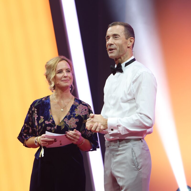 Julia Becker und Kai Pflaume stehen nebeneinander und moderieren. | © BILD der FRAU