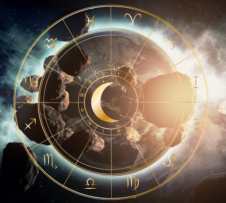 Illustration eines astrologischen Tierkreises mit goldenen Symbolen der zwölf Sternzeichen, die sich kreisförmig um ein zentrales Mond-Symbol anordnen. Im Hintergrund sind zahlreiche Asteroiden zu sehen, die durch den Weltraum treiben, begleitet von leuchtenden Nebeln und kosmischem Licht. Die Szene vermittelt eine Verbindung zwischen Astrologie und der Bewegung von Himmelskörpern wie Ceres, Pallas, Vesta und Juno im Asteroidengürtel. | © Getty Images/ blackdovfx und Artulina via Canva.com [M]