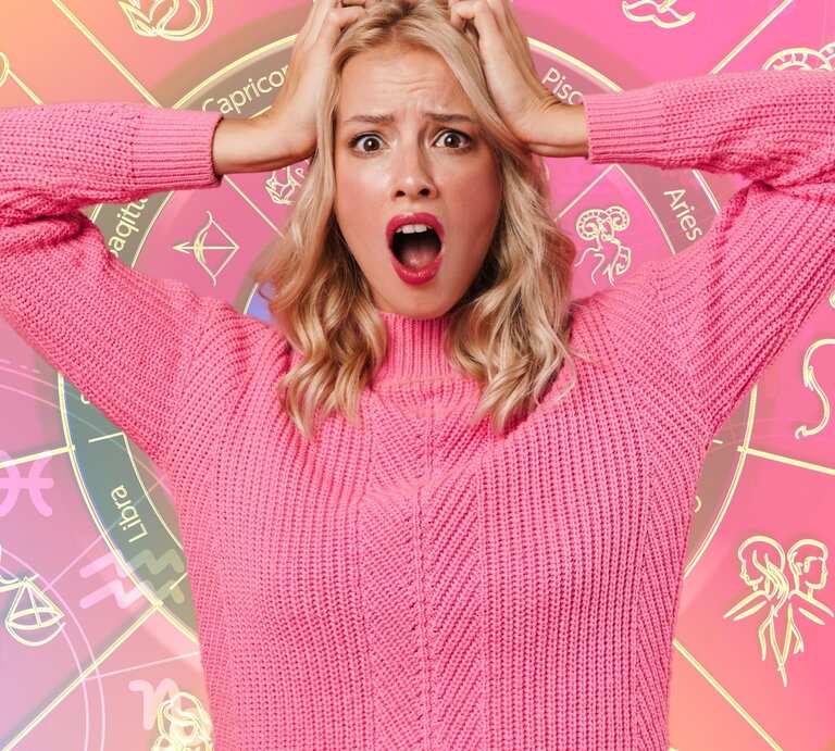 Eine junge Frau mit schulterlangem blondem Haar trägt einen pinken Pullover und fasst sich mit beiden Händen an den Kopf, während sie überrascht oder entsetzt schaut. Im Hintergrund ist ein buntes Horoskop-Rad mit den zwölf Sternzeichen und ihren Symbolen zu sehen. Die Farben sind vorwiegend pink, rosa und gelb, was dem Bild eine verspielte, astrologische Atmosphäre verleiht. | © Getty Images/ Surasak Suwanmake und Dean Drobot via Canva.com [M]