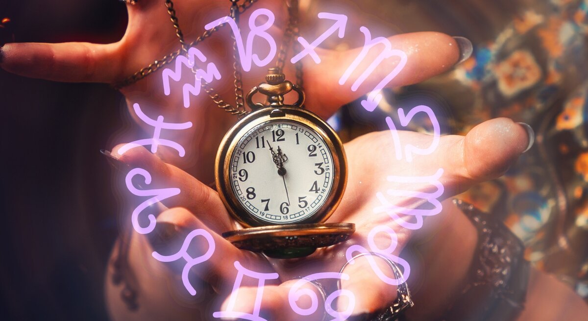 Eine Hand mit mehreren Ringen und einem Kettenarmband hält eine goldene Taschenuhr. Rund um die Uhr schweben leuchtende, violette Sternzeichen-Symbole in einem magischen Kreis. Der Hintergrund ist leicht verschwommen und zeigt bunte, gemusterte Stoffe, die eine mystische, spirituelle Atmosphäre schaffen.