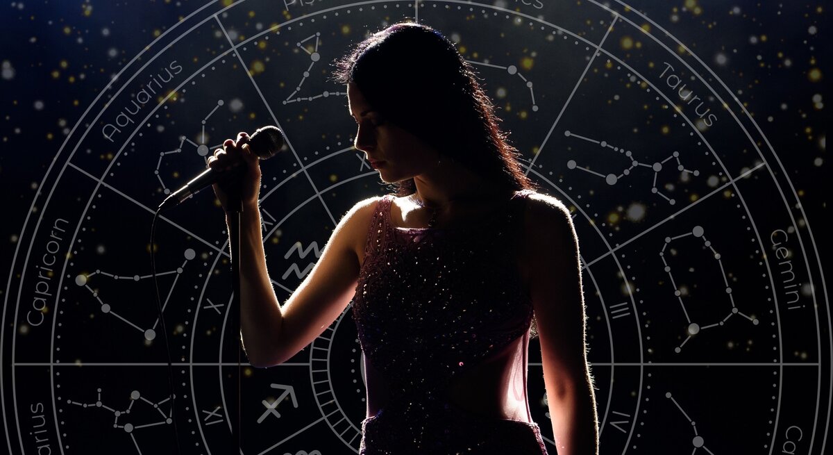 Eine Sängerin steht auf einer dunklen Bühne und hält ein Mikrofon in der Hand. Sie trägt ein funkelndes, elegantes Kleid, und ihr Gesicht ist teilweise im Schatten. Im Hintergrund leuchtet ein astrologisches Sternzeichen-Rad mit Konstellationen und Tierkreisnamen in goldenen Akzenten. Die Szene wirkt mystisch und symbolisiert eine Verbindung zwischen Kreativität, Talent und astrologischem Einfluss.