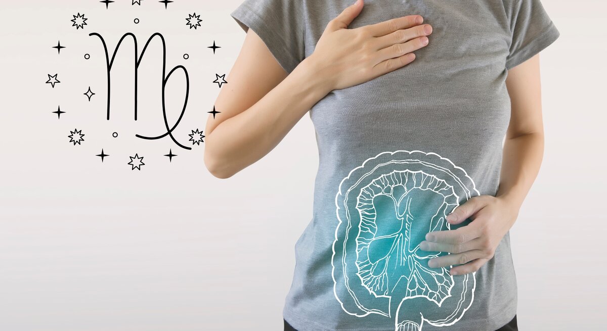 Das Bild zeigt eine Frau in einem grauen T-Shirt, die eine Hand auf ihre Brust und die andere auf ihren Bauch legt. Auf ihrem Bauch ist eine schematische Zeichnung des Verdauungssystems zu sehen, die auf das T-Shirt projiziert ist. Links neben ihr ist das astrologische Symbol für Jungfrau (Virgo) umgeben von kleinen Sternen abgebildet.
