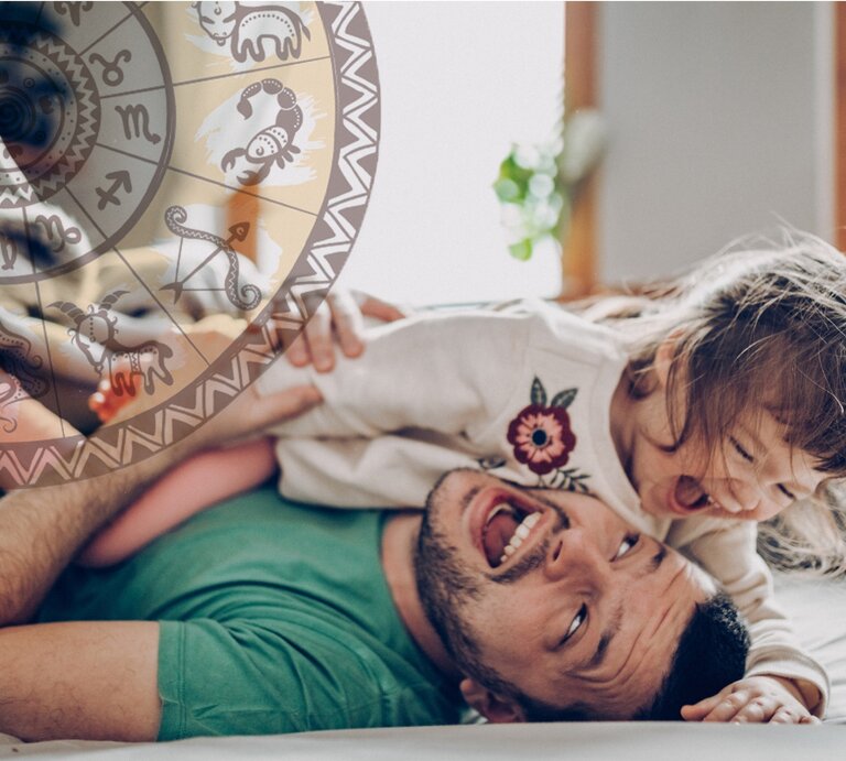 Ein fröhlicher Vater liegt auf dem Rücken und spielt mit seiner lachenden kleinen Tochter, die auf ihm liegt. Über ihnen schwebt eine transparente Scheibe mit verschiedenen astrologischen Symbolen. Sie befinden sich in einem hell erleuchteten Raum, was eine warme und liebevolle Atmosphäre schafft. | © iStock [M]
