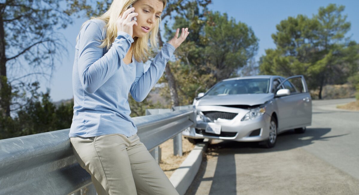 Verärgert Frau mit Handy neben ihrem kaputten Auto.