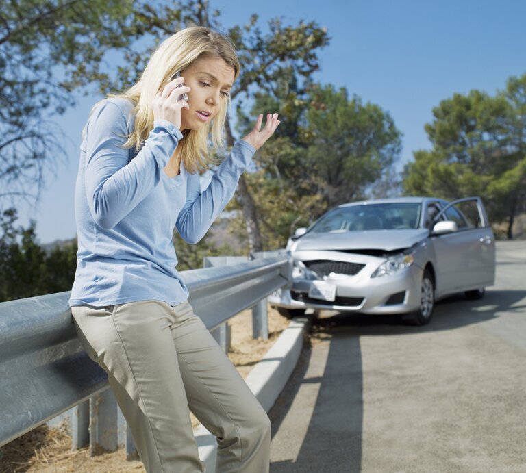 Verärgert Frau mit Handy neben ihrem kaputten Auto. | © Chris Ryan via Gettyimages