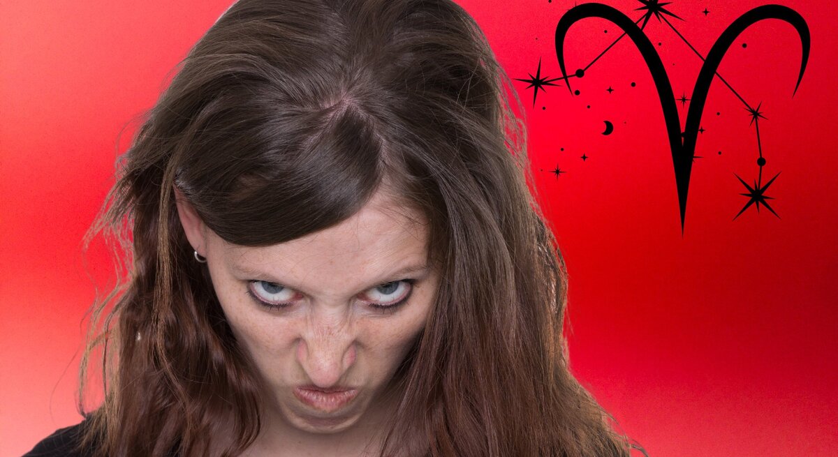 Ein Foto einer Frau mit einem kritischen oder leicht verärgerten Gesichtsausdruck. Sie hat braune Haare, trägt ein schwarzes Oberteil und blickt von unten herauf zur Kamera. Hinter ihr ist ein lebhafter roter Hintergrund mit einem Farbverlauf sowie ein großes schwarzes Symbol für das Sternzeichen Widder, umgeben vom Sternbild Widder.