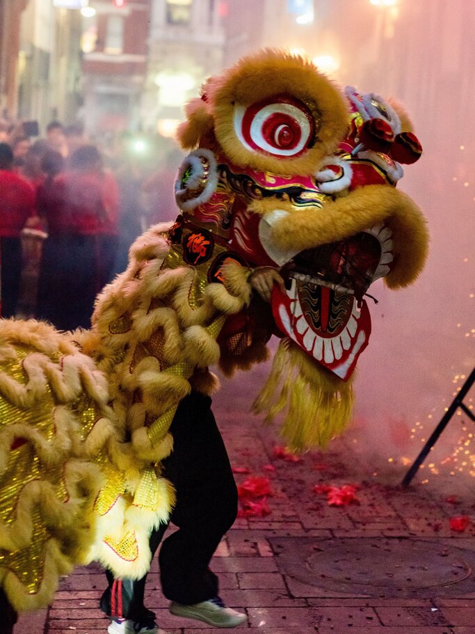 Löwentanz zum chinesischen Neujahrsfest: Ein Mann trägt eine große, bunte Drachenmaske und tanzt durch die Straßen. | © Getty Images/ Nigel Killeen