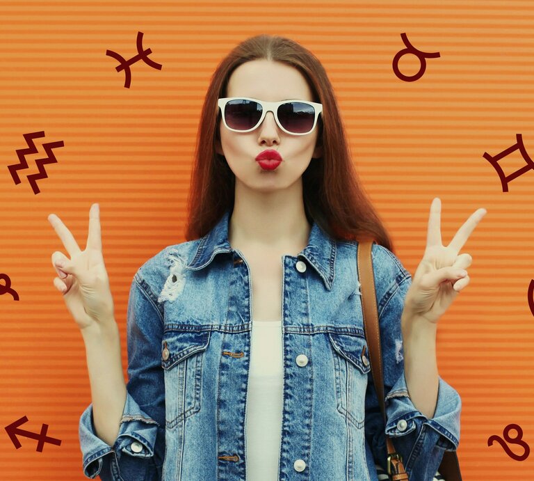 Eine junge Frau trägt eine Sonnenbrille und auffällig roten Lippenstift, sie macht einenn Kussmund und das Friedenszeichen mit beiden Händen vor einer orange gestreiften Wand. Sie trägt eine Jeansjacke und hat lange, dunkle Haare. Um sie herum sind verschiedene astrologische Symbole verteilt, darunter der Wassermann, Zwillinge, und andere, sowie das Symbol für das Sternzeichen Fische, das mit der Zahl 69 dargestellt wird. | © Getty Images/ Rohappy und Chikovnaya via Canva.com [M]