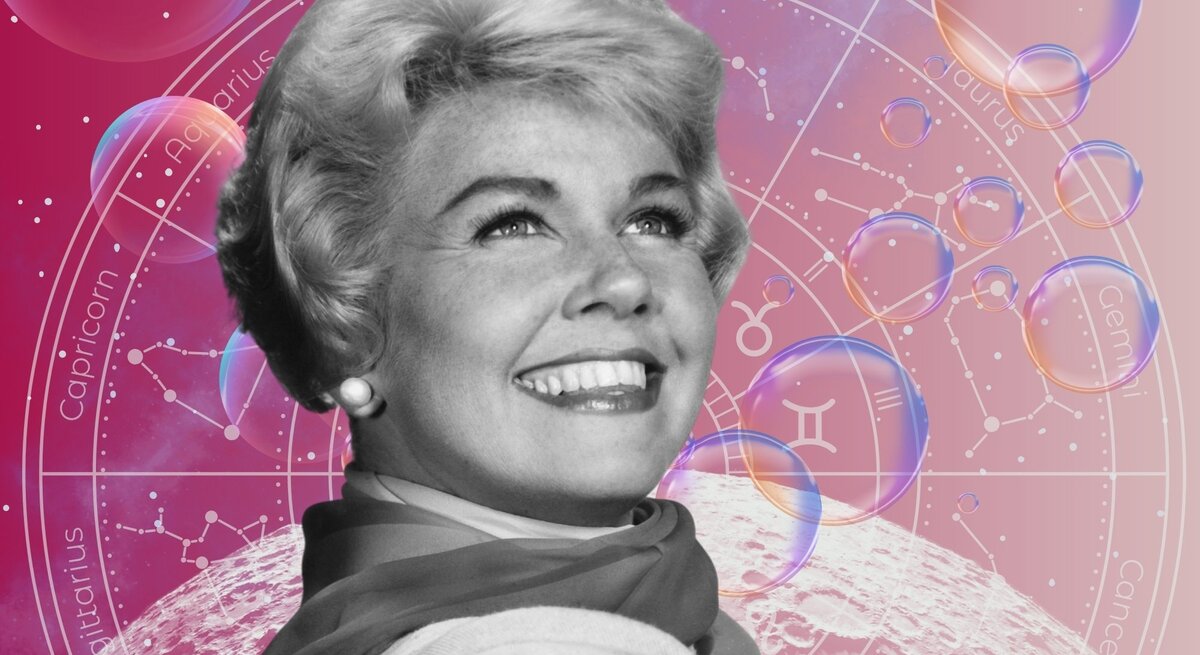 Die Schauspielerin Doris Day in schwarz-weiß steht strahlend vor einem Hintergrund, der das Universum und seine Sterne zeigt und einem Tierkreis mit den Symbolen der 12 Sternzeichen. Neben ihnen sind Seifenblasen zu sehen. Das Bild macht einen mystischen Eindruck.