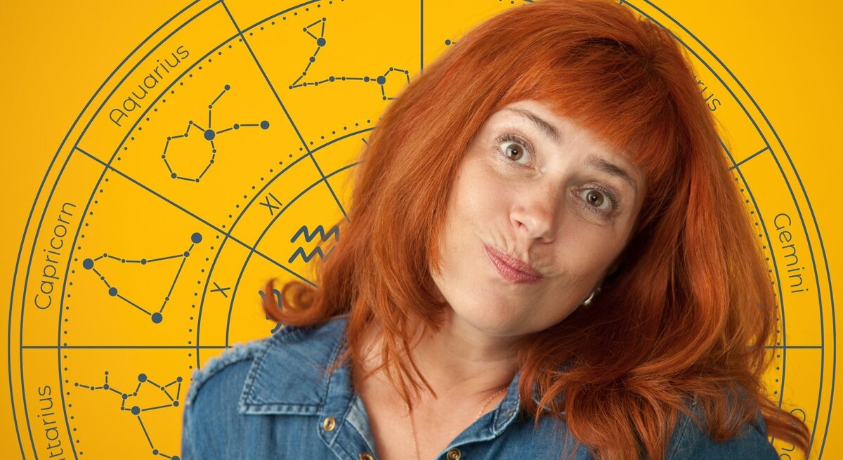 Frau mit roten Haaren in Jeanshemd steht vor einem gelben Hintergrund mit einem großen astrologischen Tierkreis. Die Sternzeichen und ihre Symbole sind kreisförmig um sie herum angeordnet. Die Frau schaut mit einem leicht schiefen Lächeln und fragendem Gesichtsausdruck in die Kamera. Das Bild vermittelt einen humorvollen, aber auch nachdenklichen Blick auf das Thema Horoskop und Pechsträhnen.