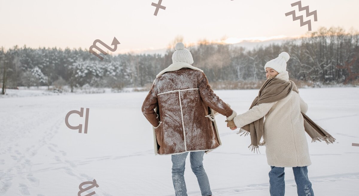 Ein verliebtes Paar hält sich an den Händen und läuft gemeinsam auf einem zugefrorenen See Schlittschuh. Beide tragen warme Winterkleidung – die Frau eine helle Jacke, eine Mütze und einen Schal, der Mann eine braune Lammfelljacke und eine Mütze. Der Schnee bedeckt ihre Kleidung, und ihre Spuren sind auf der eisigen Oberfläche sichtbar. Die Frau dreht sich mit einem glücklichen Lächeln zum Mann um. Der Hintergrund zeigt eine verschneite Winterlandschaft mit Bäumen und einem sanften Sonnenuntergang. Um das Paar schweben verschiedene astrologische Symbole, darunter für Schütze, Skorpion, Steinbock und Wassermann, was dem Bild eine mystische Note verleiht.
