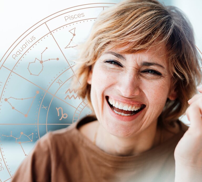 Fröhliche Frau mit kurzen, blonden Haaren lacht herzlich vor einem dezenten astrologischen Sternzeichen-Rad. Der Hintergrund ist hell und freundlich, das Rad mit den Tierkreiszeichen schimmert in sanften Pastelltönen. Das Bild strahlt Optimismus, Lebensfreude und eine positive astrologische Botschaft aus. | © Getty Images/ Westend61 und WinWin.artlab via Canva.com [M]
