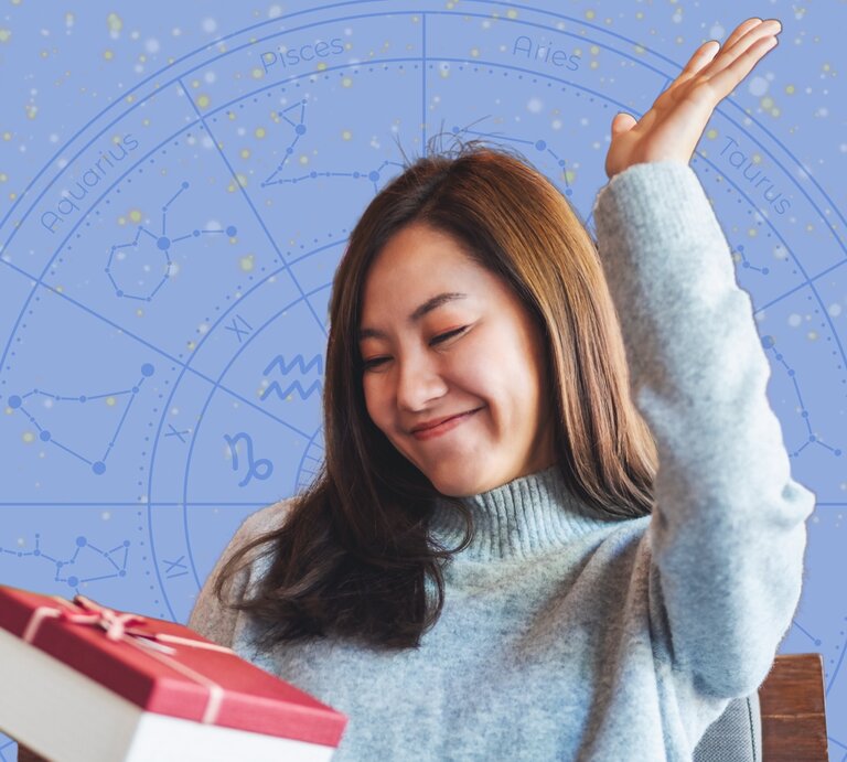 Eine junge Frau mit langem braunem Haar trägt einen hellblauen Strickpullover und hebt freudig eine Hand in die Luft, während sie ein Geschenk mit roter Schleife in der anderen Hand hält. Im Hintergrund ist eine blaue astrologische Sternzeichen-Grafik mit Konstellationen und den Namen der Tierkreiszeichen zu sehen. Die Szene strahlt Glück und Zufriedenheit aus. | ©  Farknot Architect, WinWin.artlab und Mas Water via Canva.com [M]