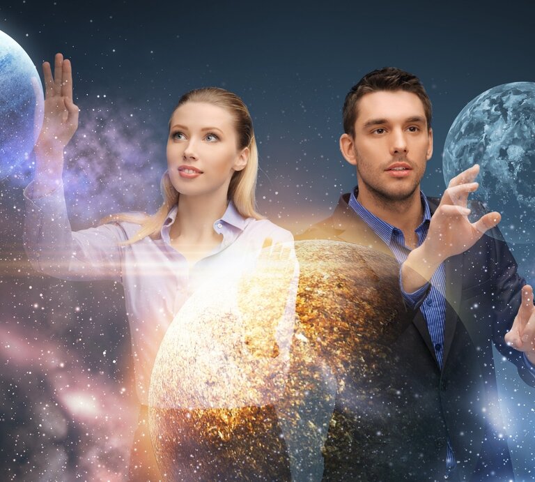 Eine Frau und ein Mann stehen vor einem kosmischen Hintergrund mit Planeten und Sternennebeln. Sie tragen Business-Kleidung und strecken ihre Hände nach den Planeten aus, als würden sie mit ihnen interagieren. Das Bild hat eine futuristische, fast holographische Anmutung, mit leuchtenden Lichteffekten, die ihre Bewegungen betonen. | © Syda Productions via Canva.com 