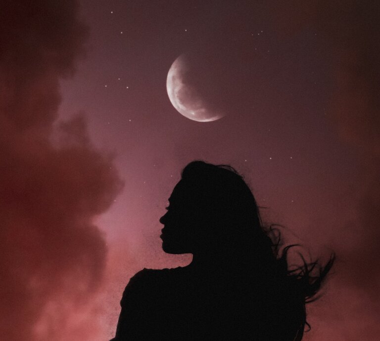 Silhouette einer Frau mit wehenden Haaren vor einem Nachthimmel mit rötlichen Wolken. Über ihr leuchtet ein zunehmender Halbmond, umgeben von kleinen Sternen. Die Szene wirkt mystisch und atmosphärisch. | © pixabay/ AlemCoksa via Canva.com [M]