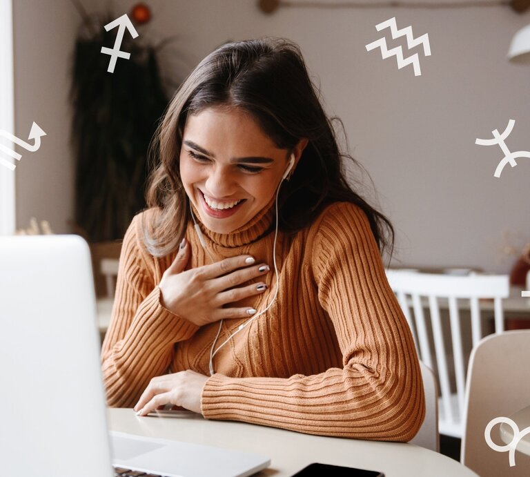 Junge Frau mit langen dunklen Haaren und einem braunen Strickpullover sitzt lächelnd vor einem Laptop. Sie trägt Kopfhörer und hält eine Hand freudig auf ihre Brust. Um sie herum sind weiße astrologische Sternzeichensymbole verteilt. | © Dean Drobot und Chikovnaya via Canva.com [M]