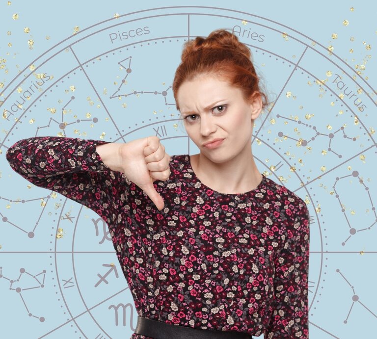 Junge Frau mit roten Haaren und floralem Oberteil, die mit einem unzufriedenen Gesichtsausdruck den Daumen nach unten zeigt. Im Hintergrund ist ein astrologisches Sternzeichenrad mit goldenen Glitzereffekten auf hellblauem Hintergrund zu sehen. | © Khosro, RanityStudio/ Ranity Design und WinWin.artlab via Canva.com [M]