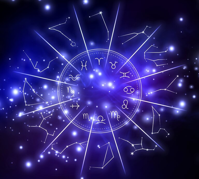 Leuchtendes astrologisches Design mit den zwölf Tierkreiszeichen in einem Kreis, umgeben von funkelnden Sternbildern und blauen Lichtpunkten auf einem tiefblauen Hintergrund. | © Africa images via canva.com