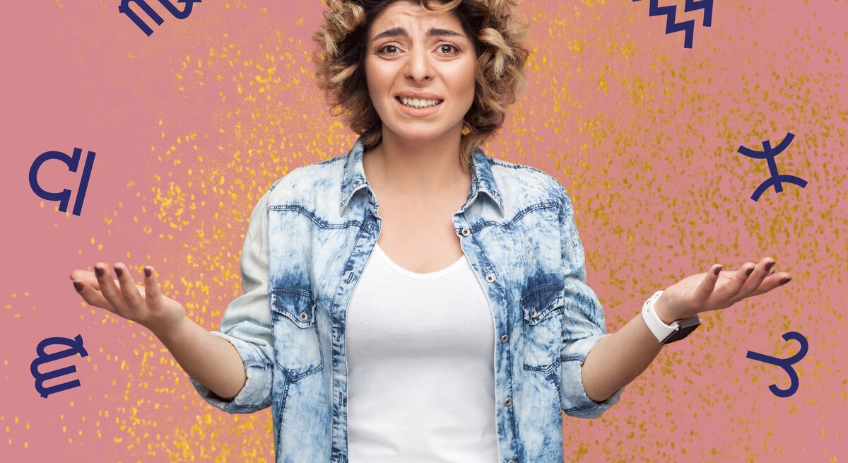 Eine Frau mit lockigen Haaren und einer Denim-Jeansjacke schaut verwirrt und gestikuliert mit ausgebreiteten Händen. Sie steht vor einem pinken Hintergrund mit goldenen Sprenkeln. Um sie herum sind Sternzeichen-Symbole wie Fische, Löwe und Wassermann verteilt. Ihr Gesichtsausdruck drückt aus, dass sie etwas nicht fassen kann.