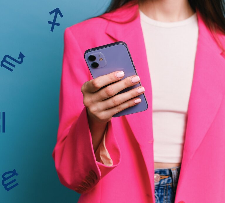 Eine Frau in einem auffälligen pinken Blazer hält ein Smartphone in der Hand. Der Hintergrund ist in einem lebendigen Blau gehalten, und astrologische Symbole schweben dezent um die Szene herum. Die Frau trägt ein schlichtes weißes Top und Jeans, ihre gepflegten Nägel sind in einem natürlichen Ton lackiert. Das Bild vermittelt einen modernen und energiegeladenen Stil mit einem Hauch von Astrologie. | © Pexels/ Anna Shvets und Chikovnaya via Canva.com [M]