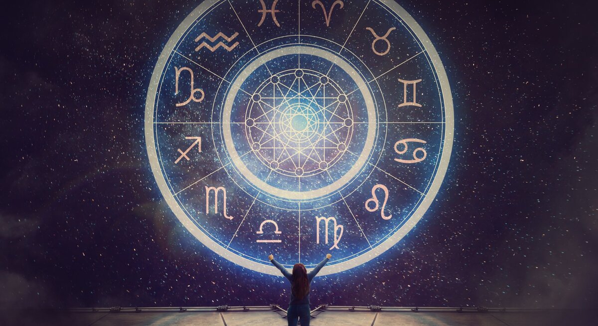 Eine Person steht vor einem großen, leuchtenden astrologischen Rad, das alle zwölf Tierkreiszeichen zeigt. Der Nachthimmel im Hintergrund ist voller funkelnder Sterne, und die Szene vermittelt eine mystische und kosmische Atmosphäre.