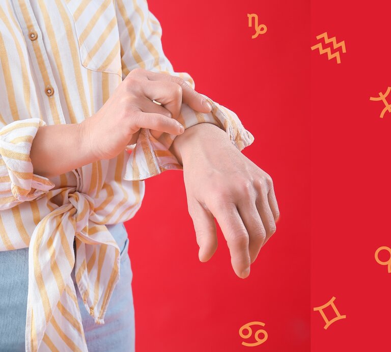 Eine Person in einer gestreiften Bluse krempelt ihren Ärmel hoch, während sie sich die Handgelenke betrachtet. Im Hintergrund sind auf einem roten Untergrund astrologische Symbole der Tierkreiszeichen zu sehen. Die Szene symbolisiert Selbstreflexion und das Durchstehen von Herausforderungen. | © Chikovnaya und pixelshot via Canva.com [M]