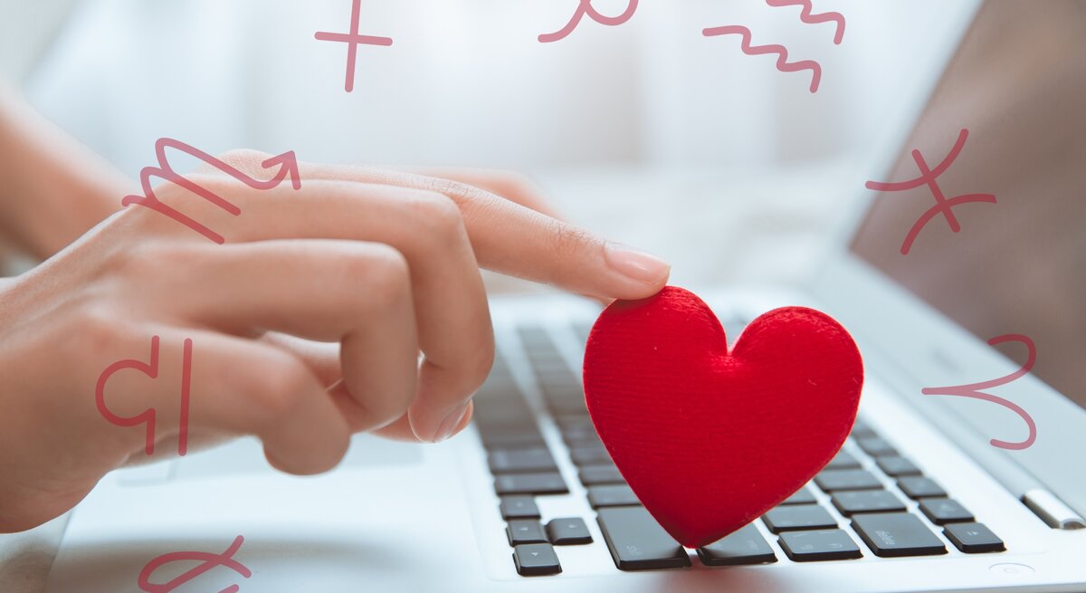 Eine Hand tippt auf eine Computertastatur, während sie ein kleines, rotes Stoffherz berührt. Um die Tastatur und die Hand schweben Symbole der Tierkreiszeichen. Das Bild symbolisiert digitale Kommunikation oder Online-Dating im Zusammenhang mit Astrologie und Liebe. Der Hintergrund ist weich und verschwommen, was eine intime und moderne Atmosphäre vermittelt.