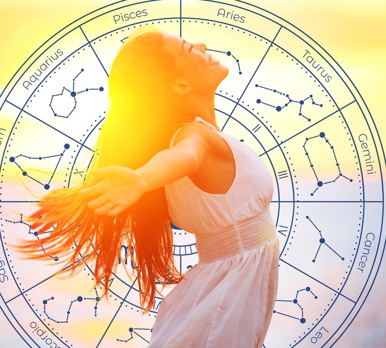 Das Bild zeigt eine Frau in einem weißen Kleid, die ihre Arme ausstreckt und den Kopf nach hinten neigt, während sie in der Sonne steht. Im Hintergrund ist ein astrologisches Rad zu sehen, das die Tierkreiszeichen und ihre entsprechenden Sternbilder darstellt. Die Sonne scheint hell und verleiht dem Bild eine warme und strahlende Atmosphäre. | © Maridav und WinWin.artlab via Canva.com [M]
