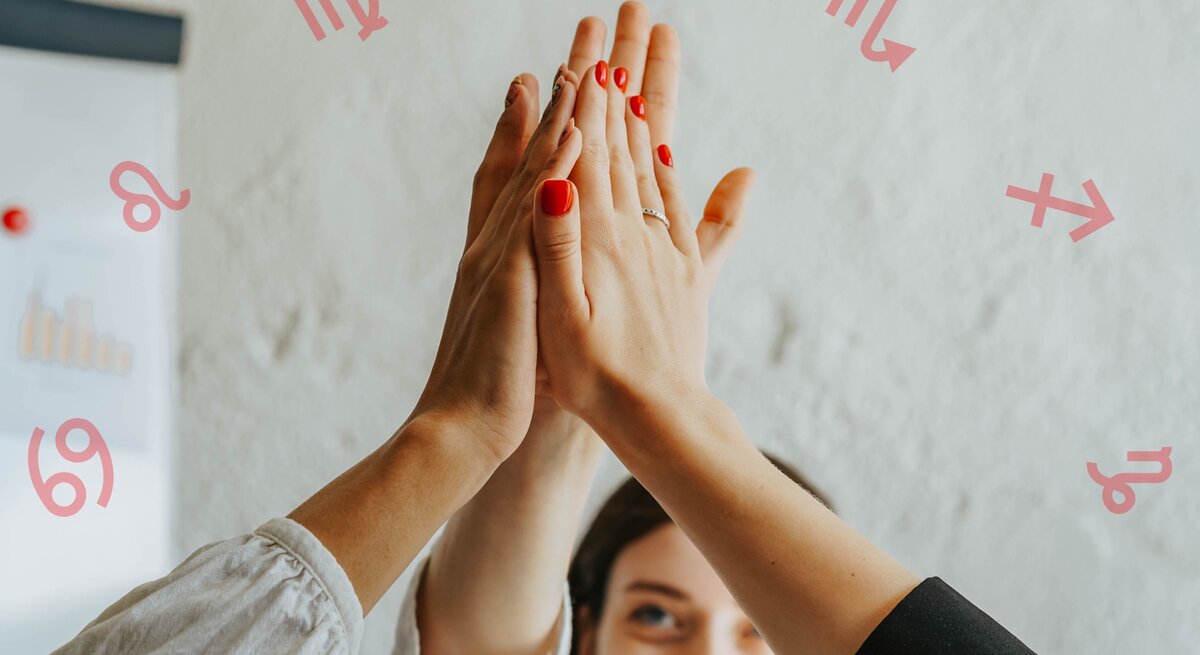 Drei Personen geben sich ein High-Five, wobei nur ihre Arme und Hände sichtbar sind. Eine Person hat rot lackierte Nägel. Im Hintergrund ist eine lächelnde Frau und eine weiße Wand mit astrologischen Symbolen der Tierkreiszeichen Löwe, Jungfrau, Waage, Skorpion, Schütze und Krebs zu sehen. Ein Diagramm ist ebenfalls teilweise sichtbar.