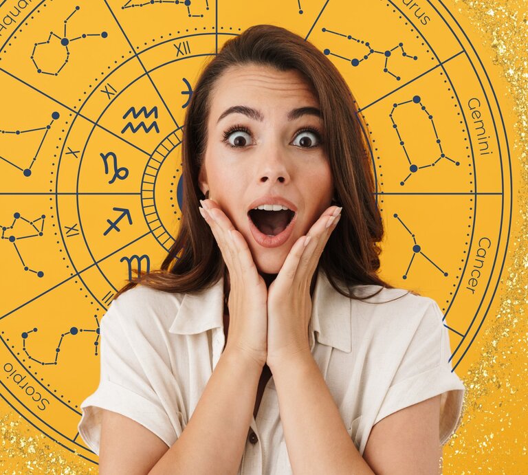 Eine überraschte Frau hält ihre Hände an ihr Gesicht. Im Hintergrund ist ein großes, gelbes Horoskop-Rad mit Sternzeichen und Konstellationen zu sehen. Die Frau trägt ein helles Hemd und steht vor dem astrologischen Symbolkreis, der mit goldenen Glitzerpartikeln verziert ist. | © Dean Drobot, JMBee Studio und WinWin.artlab via Canva.com [M]
