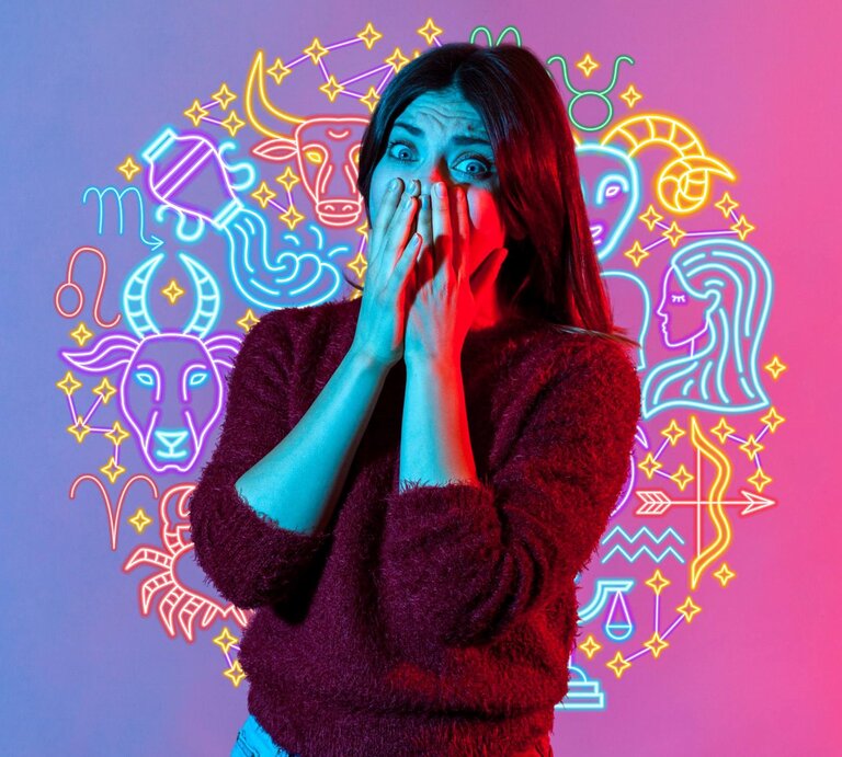 Eine Frau mit langen Haaren hält ihre Hände vor ihr Gesicht und schaut überrascht oder erschrocken. Sie trägt einen dunkelroten Pullover. Der Hintergrund ist in leuchtenden Blau- und Pinktönen gehalten und zeigt neonartige Symbole der zwölf Sternzeichen. | © 	Khosrork/Gettyimages, annaleni  via Canva.com [M]