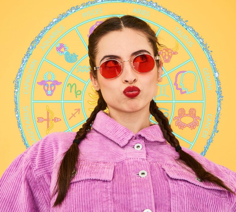 Eine Frau mit geflochtenen Haaren trägt eine rot getönte Sonnenbrille und ein lila Cordhemd. Sie macht einen spielerischen 'Duckface'-Ausdruck. Hinter ihr befindet sich ein buntes Tierkreisrad mit Symbolen, die die zwölf Sternzeichen darstellen, vor einem gelben Hintergrund. | © Flashpop/Gettyimages, jmbeestudio, annaleni  via Canva.com [M]