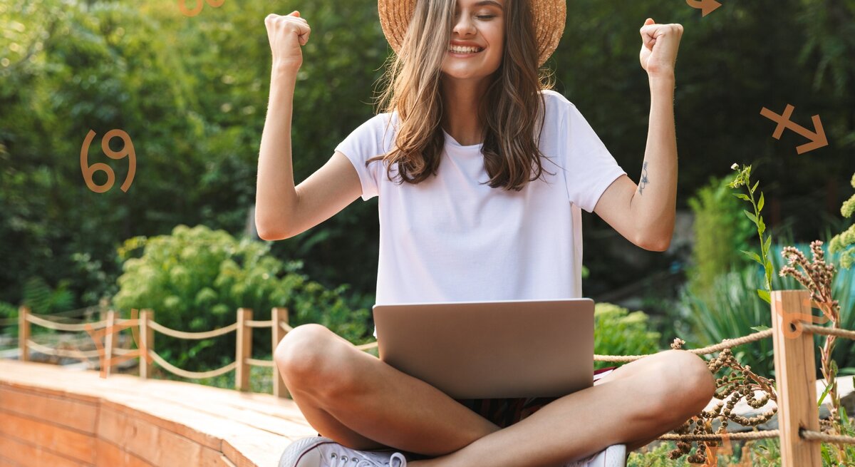 Eine junge Frau sitzt im Schneidersitz draußen in einem Garten mit einem Laptop auf dem Schoß. Sie trägt ein weißes T-Shirt und einen Strohhut und hebt triumphierend die Arme. Um sie herum sind astrologische Symbole von verschiedenen Sternzeichen platziert.