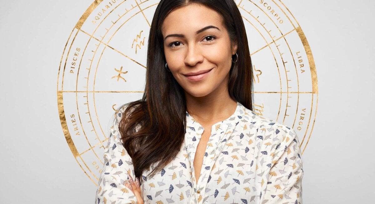  Selbstbewusste hispanische Frau vor grauem Hintergrund mit astrologischen Symbolen.
