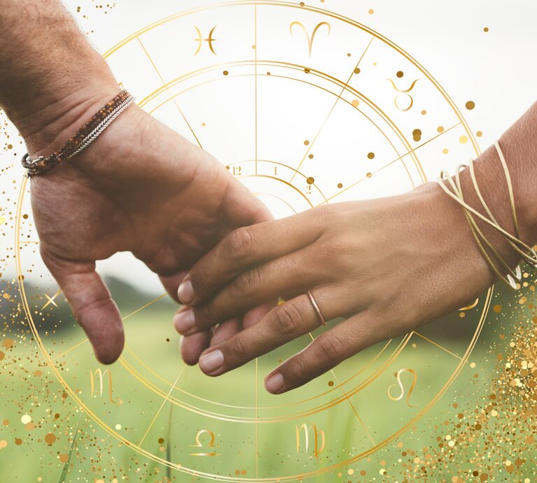 Das Bild zeigt zwei Hände, die sich berühren, vor einem Hintergrund, der an astrologische Symbole und einen Sternzeichenkreis erinnert. Die Hand links gehört einer Person, die ein silbernes und ein kupferfarbenes Armband trägt, während die rechte Hand mehrere goldene Armbänder trägt. Der Hintergrund ist in weichen, grünen Farbtönen gehalten, die an eine Wiese erinnern. Über dem Bild sind goldene Sprenkel und astrologische Symbole verteilt, was dem Bild eine mystische und romantische Atmosphäre verleiht. | © Jacob Lund, Artlulina/ Artulina und Maryna Stryhak/ Glitter via Canva.com [M]