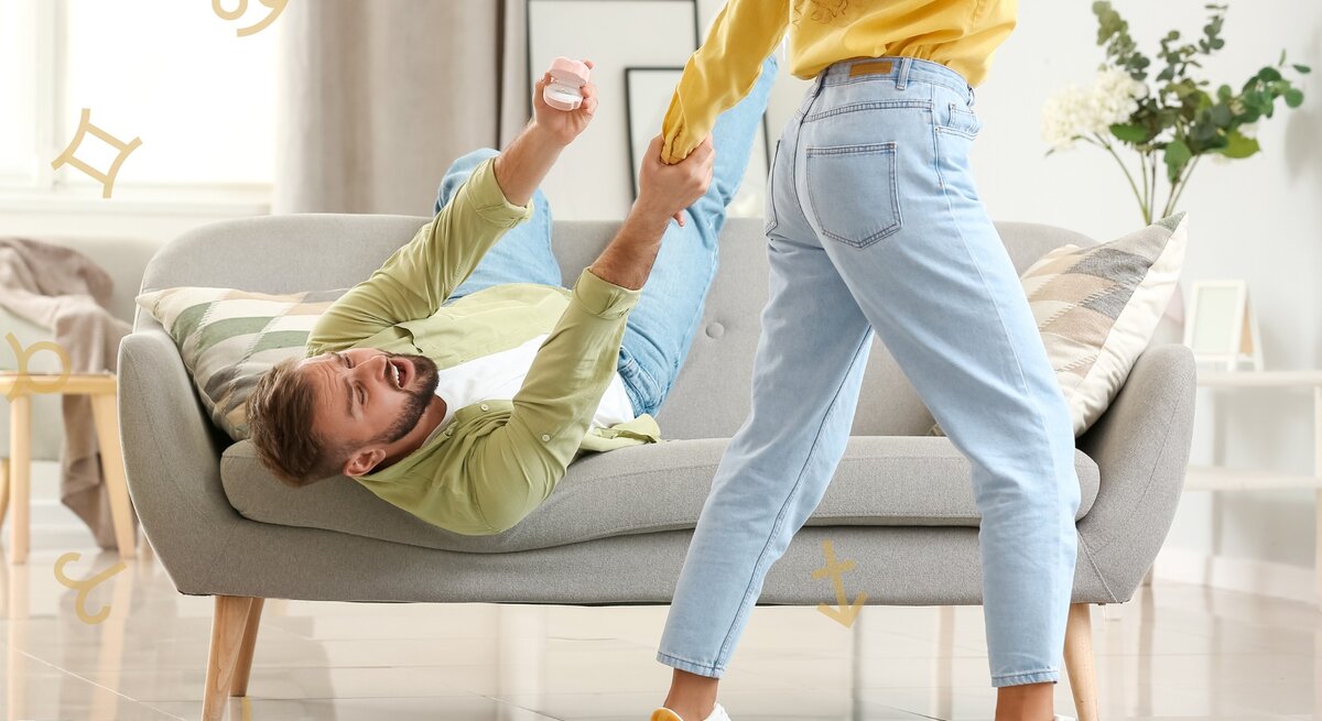 Ein unglücklicher junger Mann mit Bart liegt auf einem grauen Sofa und greift nach dem Handgelenk einer vorbeilaufenden Frau, um sie festzuhalten. Darum herum sind die astrologischen Symbole einiger Tierkreiszeichen zu sehen.