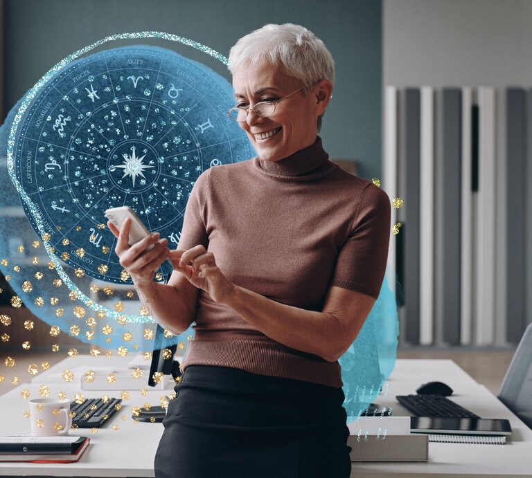 Geschäftsfrau mit grauen Haaren, die ein Smartphone benutzt und lächelt, während sie sich an den Schreibtisch lehnt. | © Getty Images/ g-stockstudio, bombdesign und tartila via Canva.com [M]