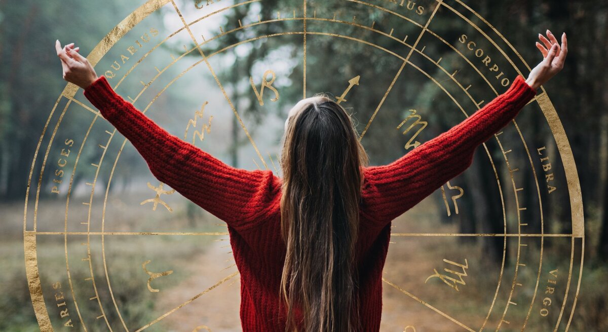 Eine Frau mit langen Haaren und einem roten Pullover steht mit dem Rücken zur Kamera und streckt die Arme nach oben, berührt dabei grafische Darstellungen des Tierkreiszeichens, die wie ein transparentes, goldenes Rad im Bild erscheinen, eingebettet in eine neblige Waldszene.