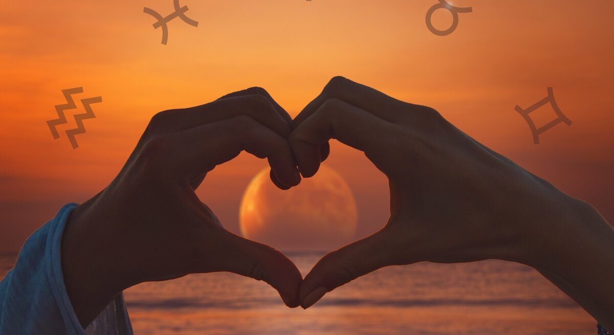Zwei Hände formen bei Sonnenuntergang ein Herz um eine aufgehende Vollmond-Silhouette am Meer. Im Hintergrund sind astrologische Symbole, einschließlich des Symbols für den Wassermann, Stier, Schütze und Zwillinge, über einen orangefarbenen Himmel verteilt.